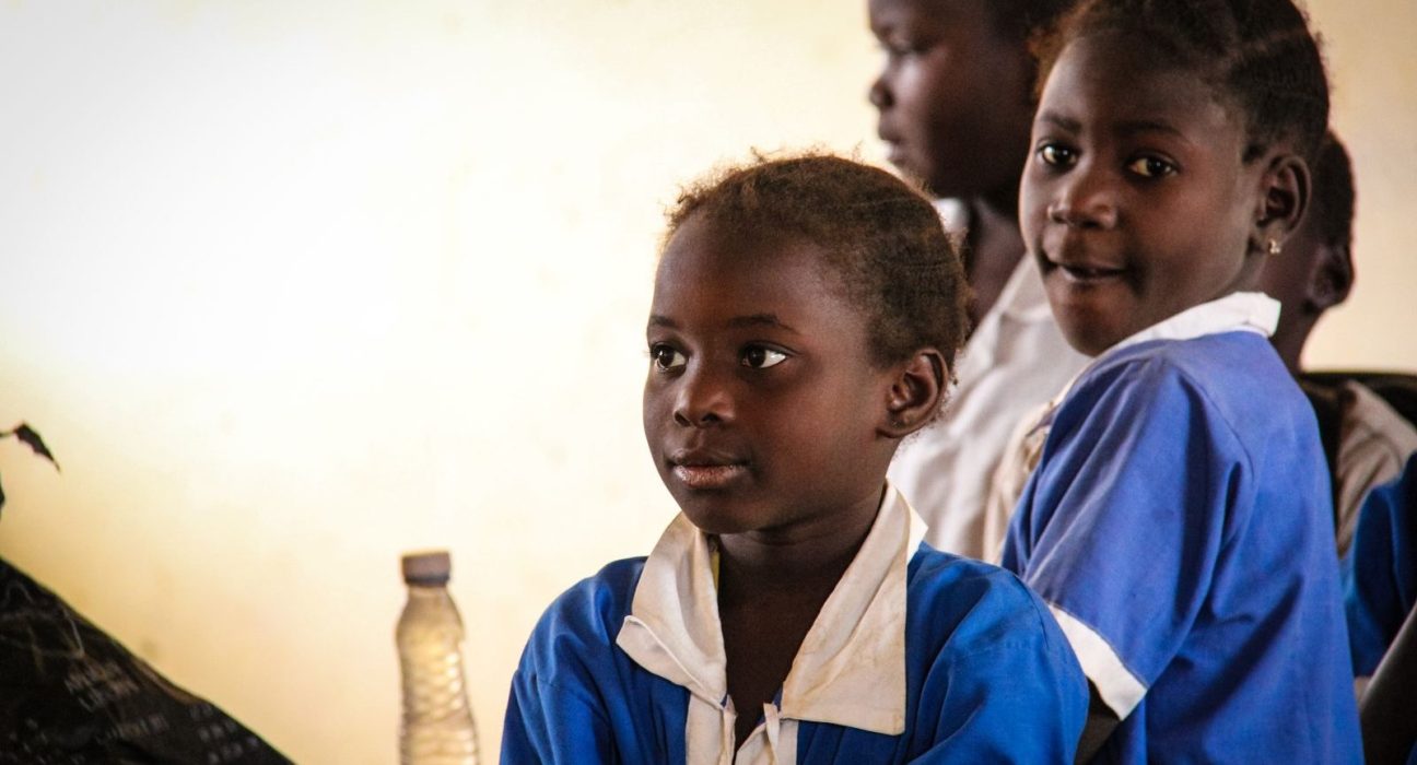 Pupils in blue school uniforms listening in a classroom