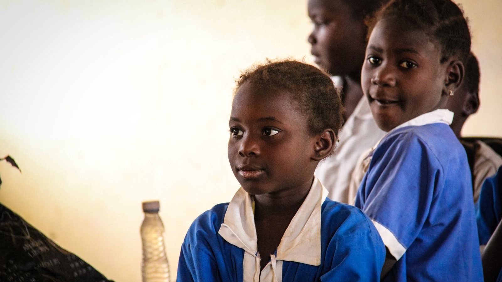 Pupils in blue school uniforms listening in a classroom