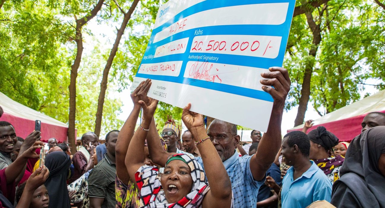 Tana River residents hold up a Britam cheque for KSh20,500,000 at the flood insurance payout event