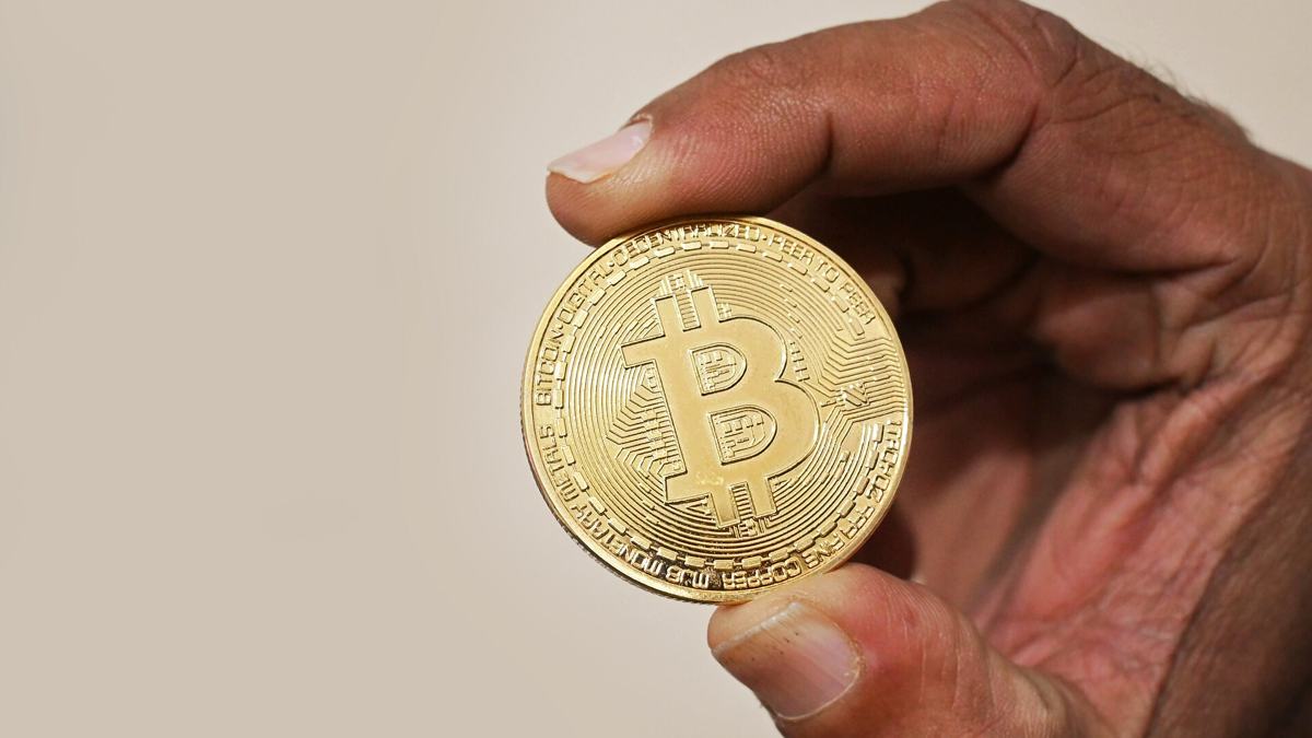Hand holding a gold-coloured Bitcoin token