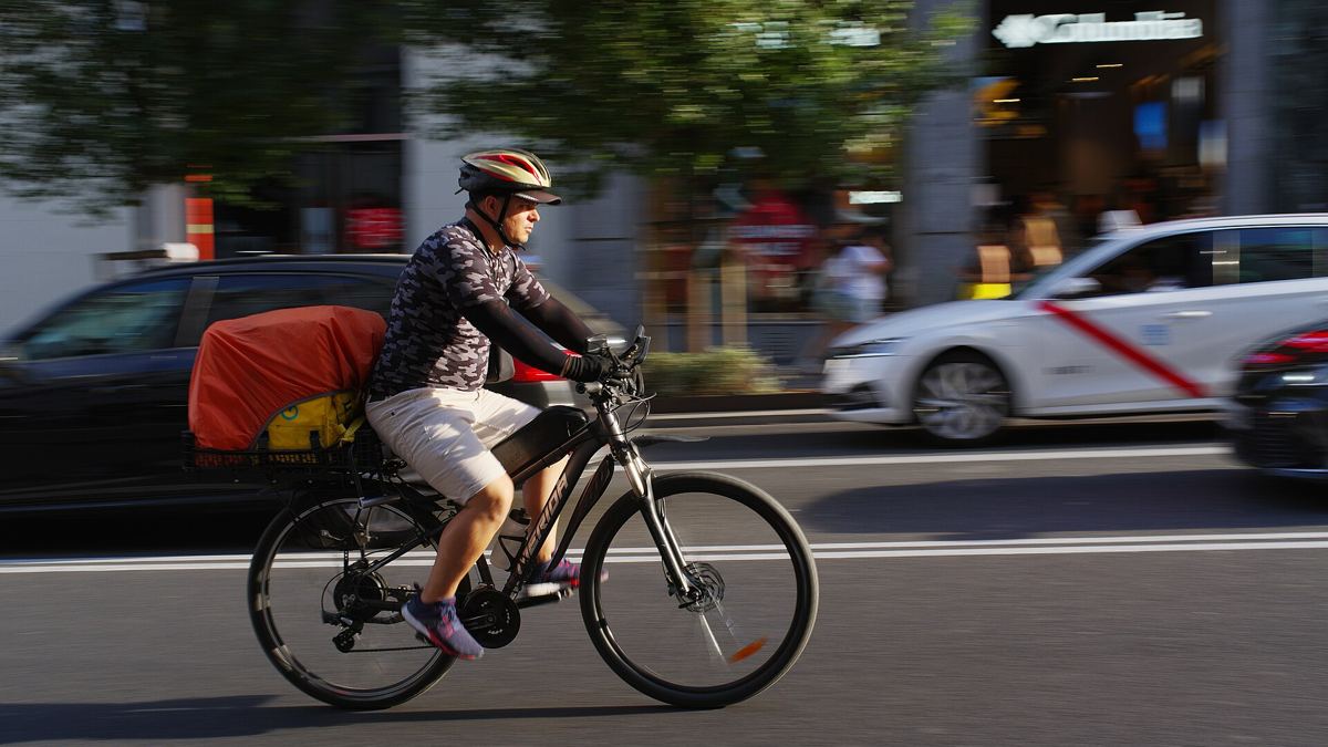 A Glovo delivery rider with the brand's yellow delivery box on a city street