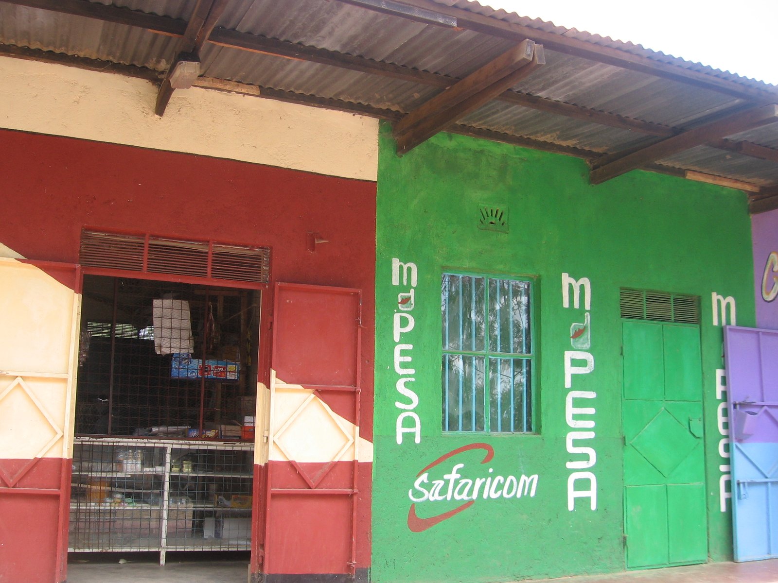 An M-Pesa agent shop painted green with Safaricom and M-Pesa signs in Kenya