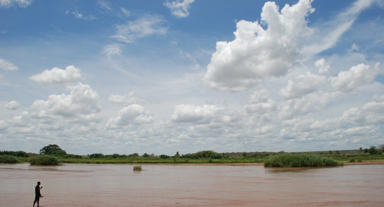 The Galana River flowing through flat green farmland in Kilifi County, Kenya